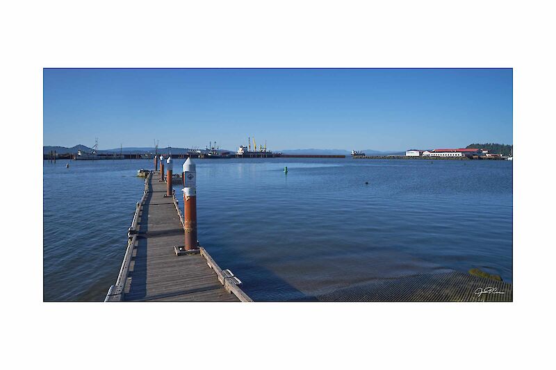 An old pier extends into the Port of Astoria