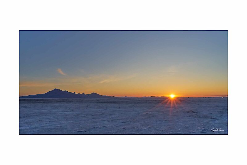 The sun rises creating a fiery red horizon at Bonneville Salt Flats in Utah.